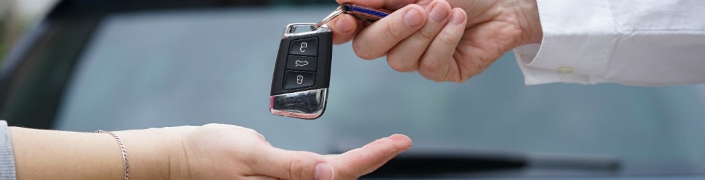 Salesperson handing keys to customer after vehicle sale.